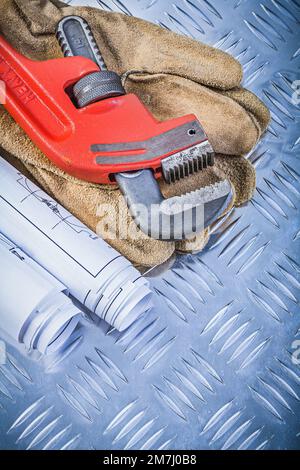 Rohrzange Baupläne Lederschutzhandschuhe auf kanalisiertem Metallhintergrund Baukonzept. Stockfoto