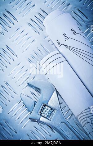 Rollende Baupläne Einstellbarer Schraubenschlüssel auf kanalgeführter Metallplatte Baukonzept. Stockfoto