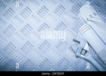 Rollende Baupläne Einstellbarer Schraubenschlüssel auf Wellblechkonstruktion Konzept. Stockfoto