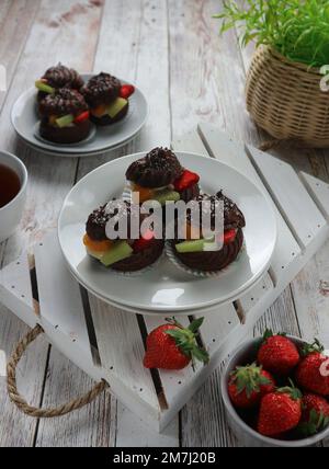 Schokoladen-eclair mit Sahnefüllung und ​​fruit-Scheiben, serviert auf einem weißen Teller Stockfoto