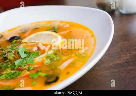 Solyanka ist eine traditionelle russische Suppe, die aus Fleisch, Fisch oder Pilzen und Gemüse wie Tomaten, Zwiebeln, Oliven und Kohl hergestellt wird. Stockfoto