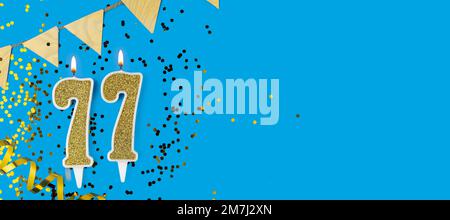 Goldene Kerze Nummer 77. Geburtstagskarte mit der Aufschrift 77 auf blauem Hintergrund. Jubiläumsfeier. Banner. Stockfoto