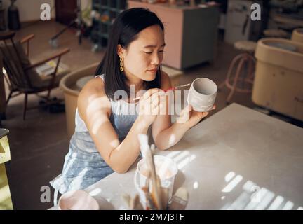 Töpferei, Kunst und Keramik mit einer asiatischen Frau in einem Designstudio oder einem kreativen Hobby als Kunsthandwerkerin. Fertigung, Muster und Künstler mit einem Stockfoto
