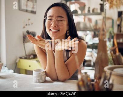 Porträt, Töpferei und Kunst mit einer asiatischen Frau in ihrem Studio oder ihrer Werkstatt für Design und kreatives Hobby. Glücklich, lächeln oder Designer mit einer Künstlerin Stockfoto