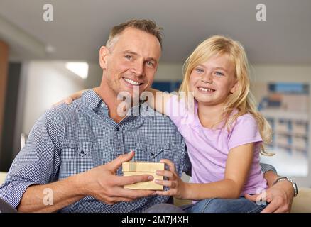 Alles gute zum Geburtstag, Dad. Porträt eines jungen Mädchens, das seinem Vater ein Geschenk macht. Stockfoto