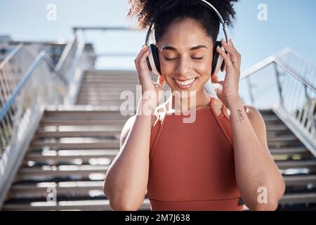 Fitness, Musik-Kopfhörer und schwarze Frau in Radio oder Podcast in der Stadt. Gesicht, Sportmeditation und glückliche Sportlerin, die Lieder hört oder Stockfoto