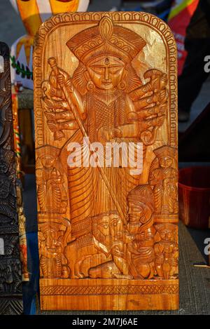 Die wunderschöne handgefertigte Holzskulptur der Göttin devi Durga wird in einem Geschäft mit verschwommenem Hintergrund zum Verkauf ausgestellt. Indische Kunst und Kunsthandwerk. Stockfoto