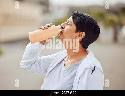 Fitness, Läufer oder alte Frau, die Wasser trinkt, mit Sportzielen, die sich in der Pause ausruhen oder entspannen. Gesunde, müde oder durstige ältere Person trinkt natürlich Stockfoto