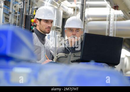 Erfahrener leitender Ingenieur berät jungen Konstrukteur in der Fabrik Stockfoto