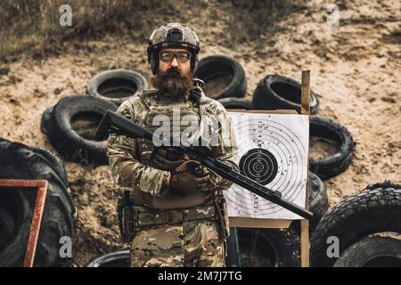 Reifer Soldat, der in der Nähe des Schießziels steht, mit Gewehr in den Händen Stockfoto
