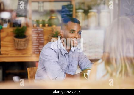Ich bin so froh, dass wir uns treffen konnten. Ein junger Mann, der mit seiner Freundin Kaffee trinkt. Stockfoto