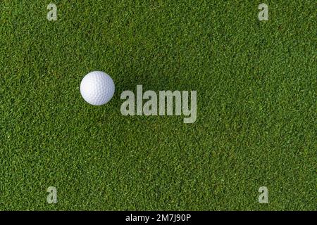 Blick von oben auf den weißen Golfball, der auf einem hellen, grünen Rasen auf einem für das Spiel vorbereiteten Golfplatz platziert wird Stockfoto