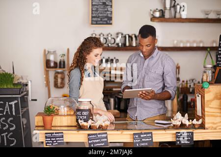 Das Café kabellos betreiben. Junge Barista, die ein digitales Tablet in einem Café verwenden. Stockfoto