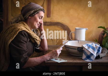 Eine Frau in authentischem Bauernrenaissance-Kostüm, die einen Brief liest Stockfoto