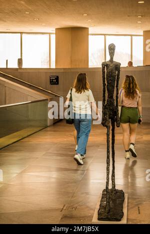 Zwei Frauen, die an Skulpturen von Alberto Giacometti vorbeigehen: Walking man II, 1960, Upper Level - Bridge, National Gallery of Art - East Building, Washingto Stockfoto