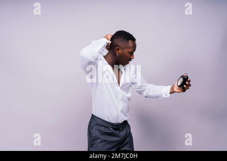 Zeitmanagementkonzept. Schockierter Schwarzer, der die Wanduhr in der Hand hält, läuft die Zeit davon. Stockfoto