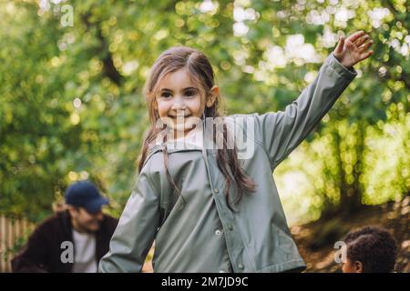 Glückliches Mädchen in Jacke genießt es, während es im Park spielt Stockfoto