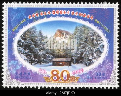 2022 Nordkorea-Stempel. Kim Jong Il zum 80. Geburtstag mit Baekdusanischem geheimen Camp-Gebäude und Berg mit Propagandaslogans Stockfoto