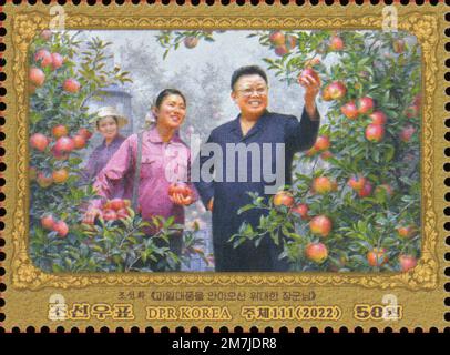 2022 Nordkorea-Stempel. Kim Jong Il zum 80. Geburtstag von 1942-2011. Anführer, der Apfelgarten inspiziert. Stockfoto