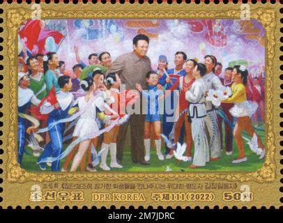 2022 Nordkorea-Stempel. Kim Jong Il zum 80. Geburtstag von 1942-2011. Der Führer besucht eine Gruppe junger Tänzer. Stockfoto