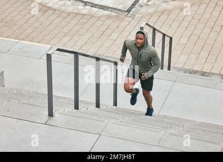 Läufer, Fitness- und Stadttreppe mit einem schwarzen Sportler in der Stadt für ein Cardio- oder Ausdauertraining. Training, Bewegung oder Motivation bei einem Mann Stockfoto