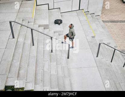 Fitness, müde oder schwarzer Mann, der auf Treppen für Training, Training oder Herz-Kreislauf-Training in Chicago, USA, geht. Mission, Denkweise oder gesunder Sportler in Hoodie Stockfoto