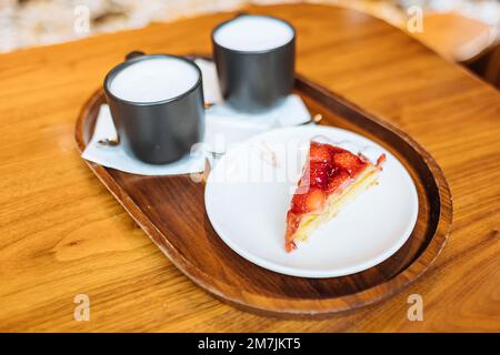 Erdbeertorte und zwei Starbuck-Kaffeetassen mit Cappuccino auf einem Tablett im Starbucks Reserve Roastery Shop in Mailand, Italien Stockfoto