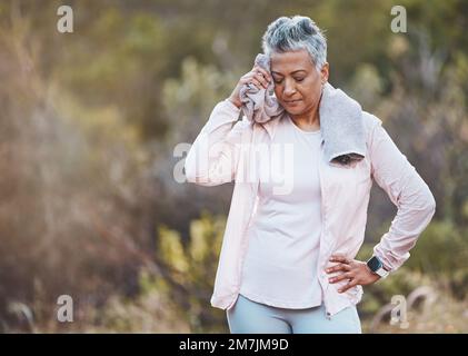 Seniorin, müde und ein Handtuch zum Schwitzen im Park nach einem Training oder einem Workout-Modell. Sportliche Fitness, Pause und Ermüdung, erschöpfte und ältere Frau Stockfoto