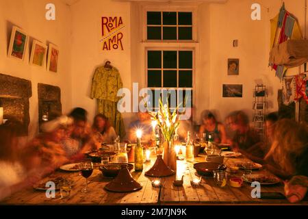 Eine Gruppe von Menschen versammelte sich bei einem Familienessen, um einen Feiertag am Holztisch zu feiern Stockfoto