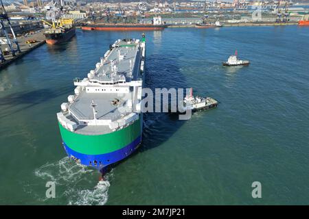 YANTAI, CHINA - 10. JANUAR 2023 - Ein Auto-Ro-Schiff, unterstützt von Schleppbooten, fährt vom Hafen von Yantai, Ost-Chinas Provinz Shandong, am 9. Januar 202 ab Stockfoto