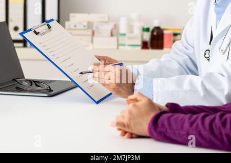 Foto eines selbstbewussten männlichen Arztes, der einem Patienten in einem Krankenhaus während des Tages Testergebnisse zeigt Stockfoto
