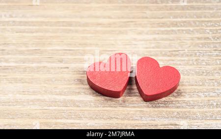 Zwei rote handgemachte hölzerne geschnitzte Herzen auf Holz Hintergrund, Paar Beziehung Valentinstag-Konzept Stockfoto