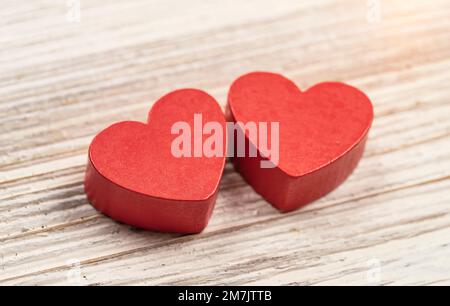 Zwei rote handgemachte hölzerne geschnitzte Herzen auf Holz Hintergrund, Paar Beziehung Valentinstag-Konzept Stockfoto
