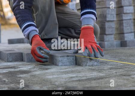 Auf Sandgrundlagen des Hauses Hofmeister legt graue Betonpflastersteine in Reihen. Stockfoto