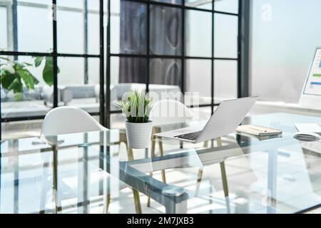 Laptop auf einem gläsernen Schreibtisch in einem modernen Büro. Stockfoto