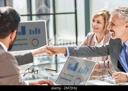 Glückliche Kollegen, die sich die Hand schütteln. Schließen. Stockfoto
