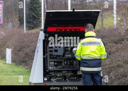 10. Januar 2023, Sachsen, Heidenau: Ein Mitarbeiter der Polizei des Bezirks Sächsische Schweiz-Ostererzgebrige steht vor einem mobilen Verkehrsüberwachungssystem in Heidenau. Dadurch wird der Straßenverkehr gemessen, und bei Überschreitung der Geschwindigkeitsbegrenzung wird ein optisches rotes Blinken in den Verkehrsbereich gesendet. Foto: Daniel Schäfer/dpa Stockfoto