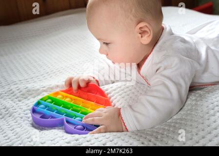 Happy Kid spielt mit Pop IT. Neugeborenes Baby spielt mit einfachen Dimple. Das flexible Sensory Fidget Push-Bubble Spielzeug ist gut für die Baby-Entwicklung. Litt Stockfoto