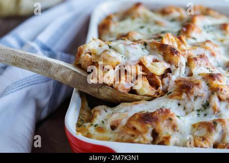 Löffel mit hausgemachtem Tortellini-Nudelauflauf, garniert mit gehackter frischer Petersilie und geschmolzenem goldenen Mozzarella-Käse. Selektiver Fokus. Stockfoto