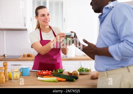 Frau, die ihrem Mann vor der Arbeit einen Behälter mit Essen gibt Stockfoto