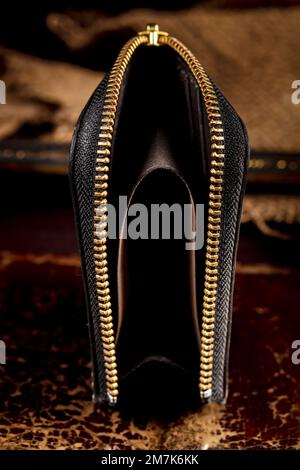 Ledergeldbörse mit goldenem Reißverschluss auf dunklem Hintergrund. Stockfoto