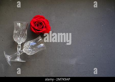 Zwei Gläser mit roter Rose in der Nähe auf grauem Hintergrund Stockfoto