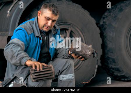 Automechaniker repariert Lkw. Professionelle Reparatur und Diagnose von Frachttraktoren und -Ausrüstung. Der Mechaniker in der Werkstatt berücksichtigt Ersatzteile. Stockfoto