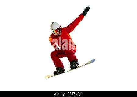 Porträt eines aktiven Mannes, Snowboarders in Uniform, der auf einem Snowboard fährt, isoliert vor weißem Studiohintergrund. Hochsprung. Konzept des Wintersports, Action Stockfoto