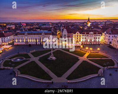 Blick auf den Union Square aus der Vogelperspektive mit den umliegenden Gebäuden im barocken Stil und dem feurigen Himmel bei Sonnenuntergang. Das Foto wurde am 6. Januar 2023 in Timisoara aufgenommen. Stockfoto