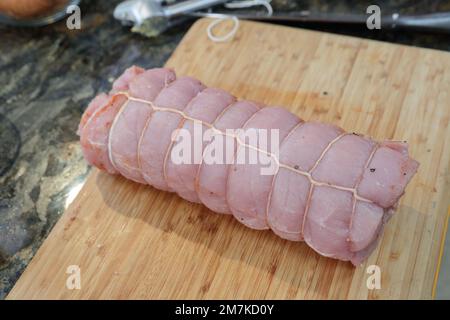 Rohes Kotelettfleisch, gebunden mit Küchenzwirn, zubereitet zum Braten. Stockfoto