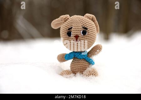 Gestricktes Häschen im Schnee auf verschwommenem Waldhintergrund, Grußkarte. Symbol des chinesischen Neujahrs 2023 Stockfoto