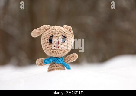 Gestricktes Häschen im Schnee auf verschwommenem Waldhintergrund, Grußkarte. Symbol des chinesischen Neujahrs 2023 Stockfoto