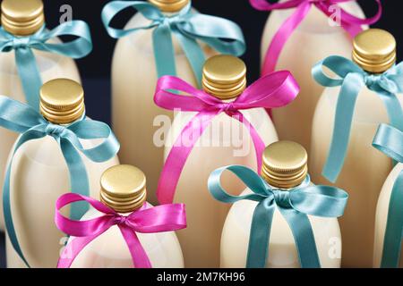 Hausgemachter Eierstockschießen in Flaschen mit blauen und rosa Schleifen auf dunklem Hintergrund Stockfoto