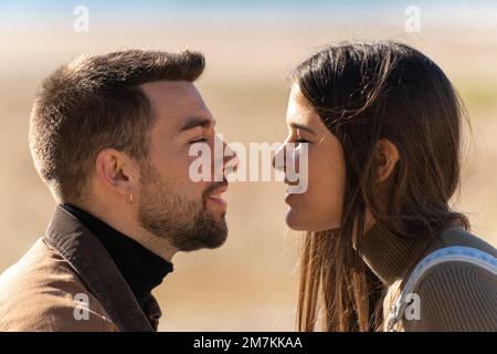 Ein verliebtes junges Paar sieht sich an, wie sie lächeln und den valentinstag feiern Stockfoto